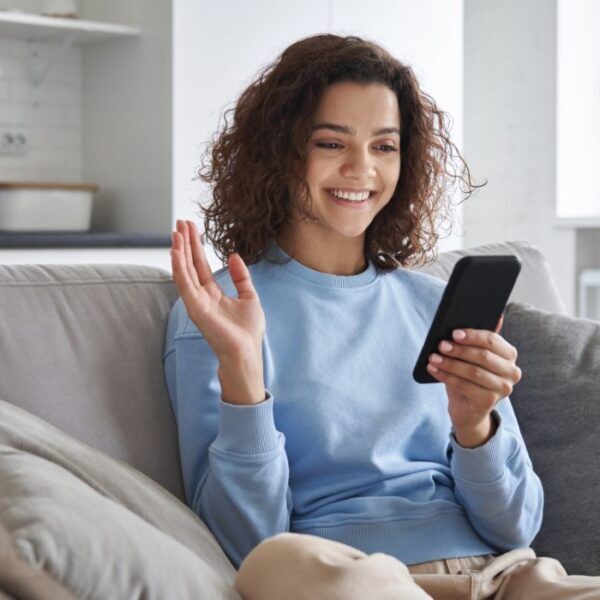 Smiling Woman Using Smartphone On Couch Representing User-Friendly Priority Mobile Erp App With Real-Time Access To Business Data, Remote Work, And Mobile Productivity Features